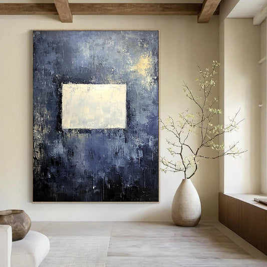 Bold contemporary abstract painting features a muted gray wall with dark blue and yellow tones highlighted by a central white square, creating a striking visual impact. DLZ0453