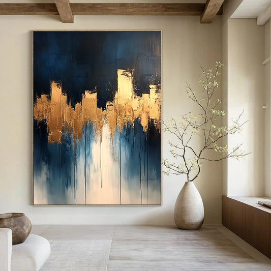 Contemporary abstract painting features dripping white and gold paint on canvas with vibrant blue tones and metallic gold leaf accents. DLZ0333