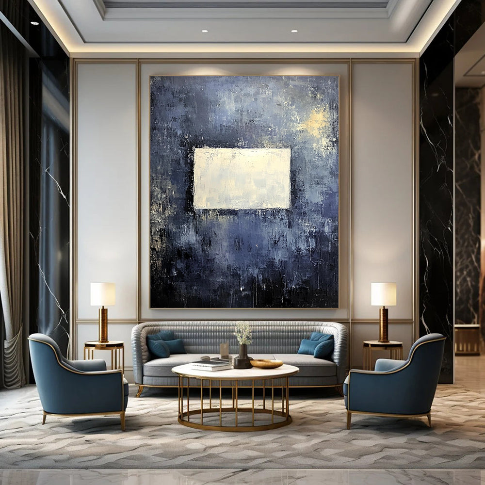 Bold contemporary abstract painting features a muted gray wall with dark blue and yellow tones highlighted by a central white square, creating a striking visual impact. DLZ0453