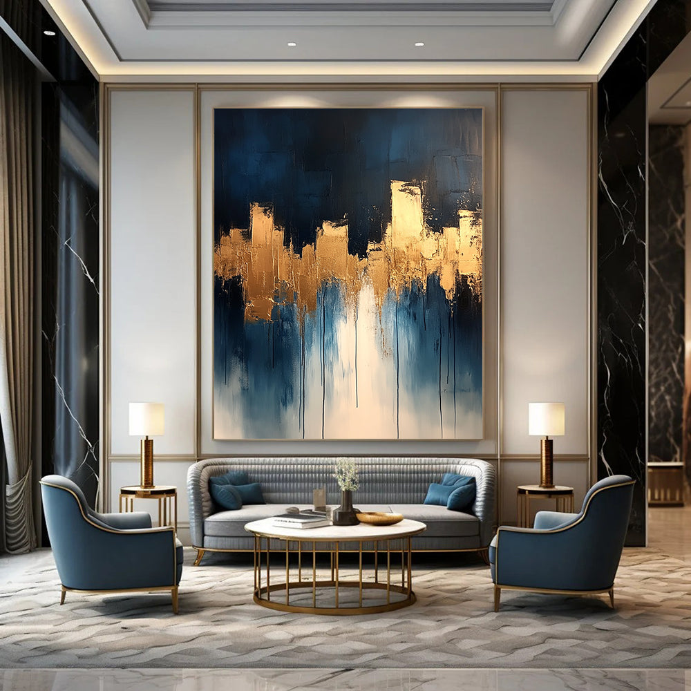 Contemporary abstract painting features dripping white and gold paint on canvas with vibrant blue tones and metallic gold leaf accents. DLZ0333