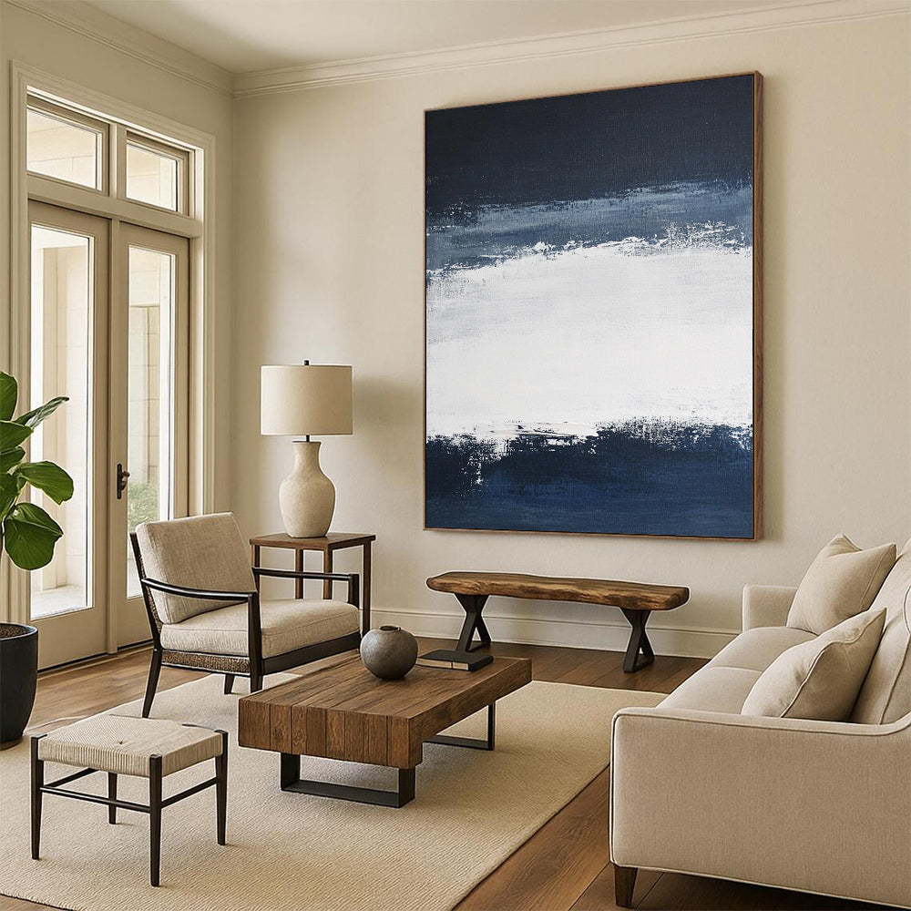 Large contemporary abstract painting featuring broad brush strokes in white and navy blue creating a tranquil atmosphere with a serene dark sky and soft gray clouds. DLZ0546