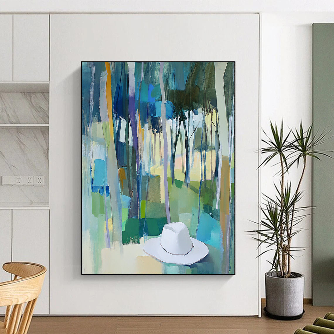 Contemporary abstract painting featuring trees in vibrant blue, green, and yellow hues with a white hat resting on the ground. DLZ0897