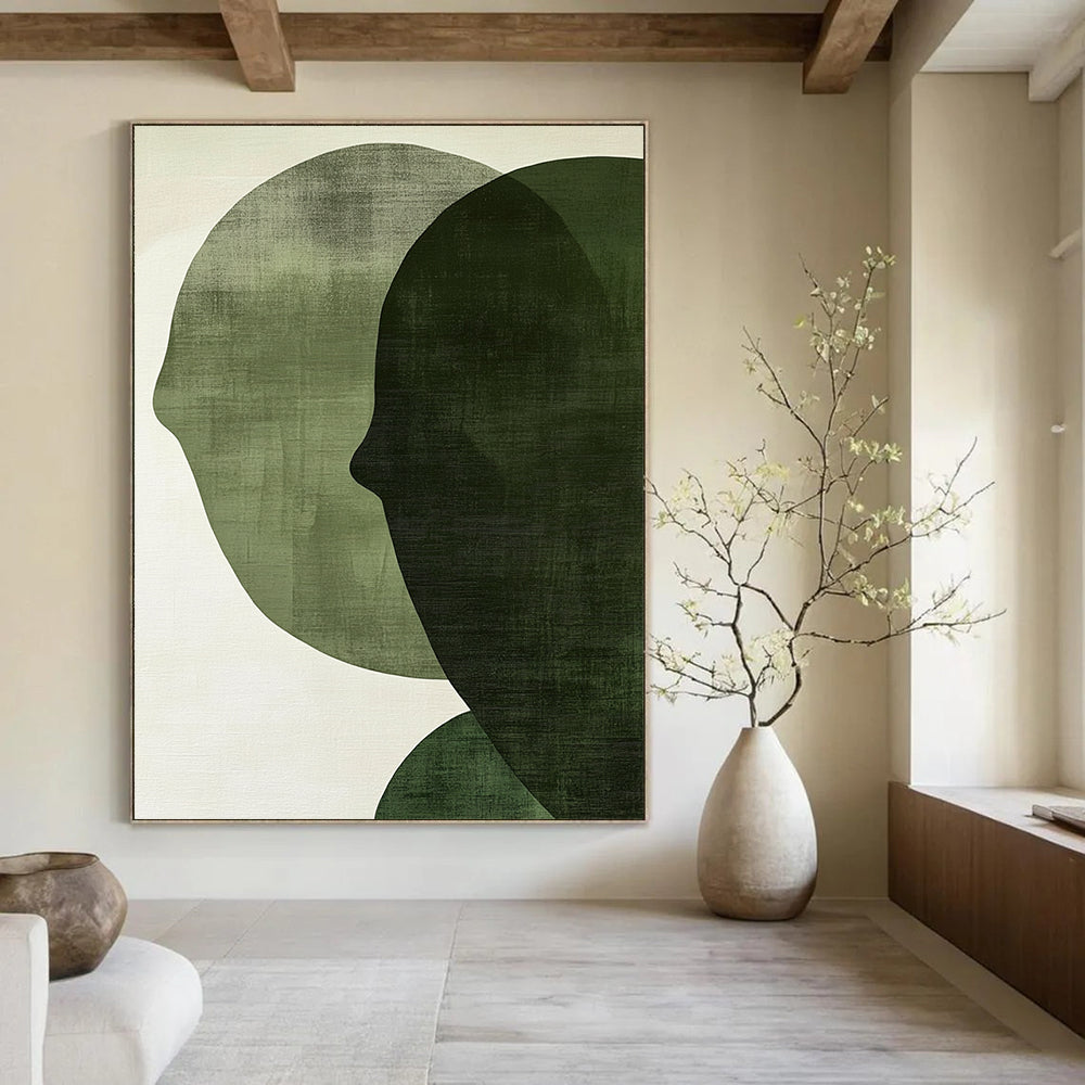 Contemporary abstract art features large forest green shapes on an off-white textured background, creating faces that symbolize connection and balance. DLZ1364