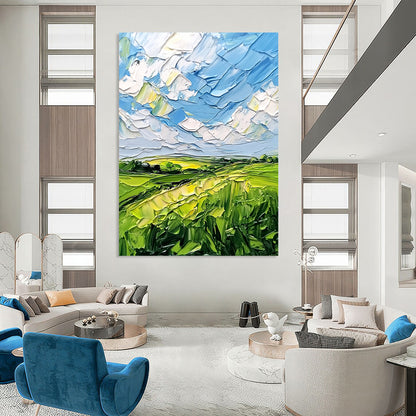 Contemporary abstract artwork featuring lush green fields and a vibrant blue sky with clouds, textured with bold impasto strokes. DLZ0484