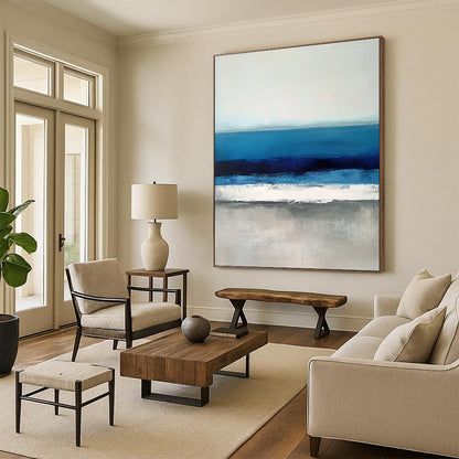 Large contemporary abstract painting featuring soft blues and grays capturing serene sea waves with a hint of deep blue for added depth. DLZ1359