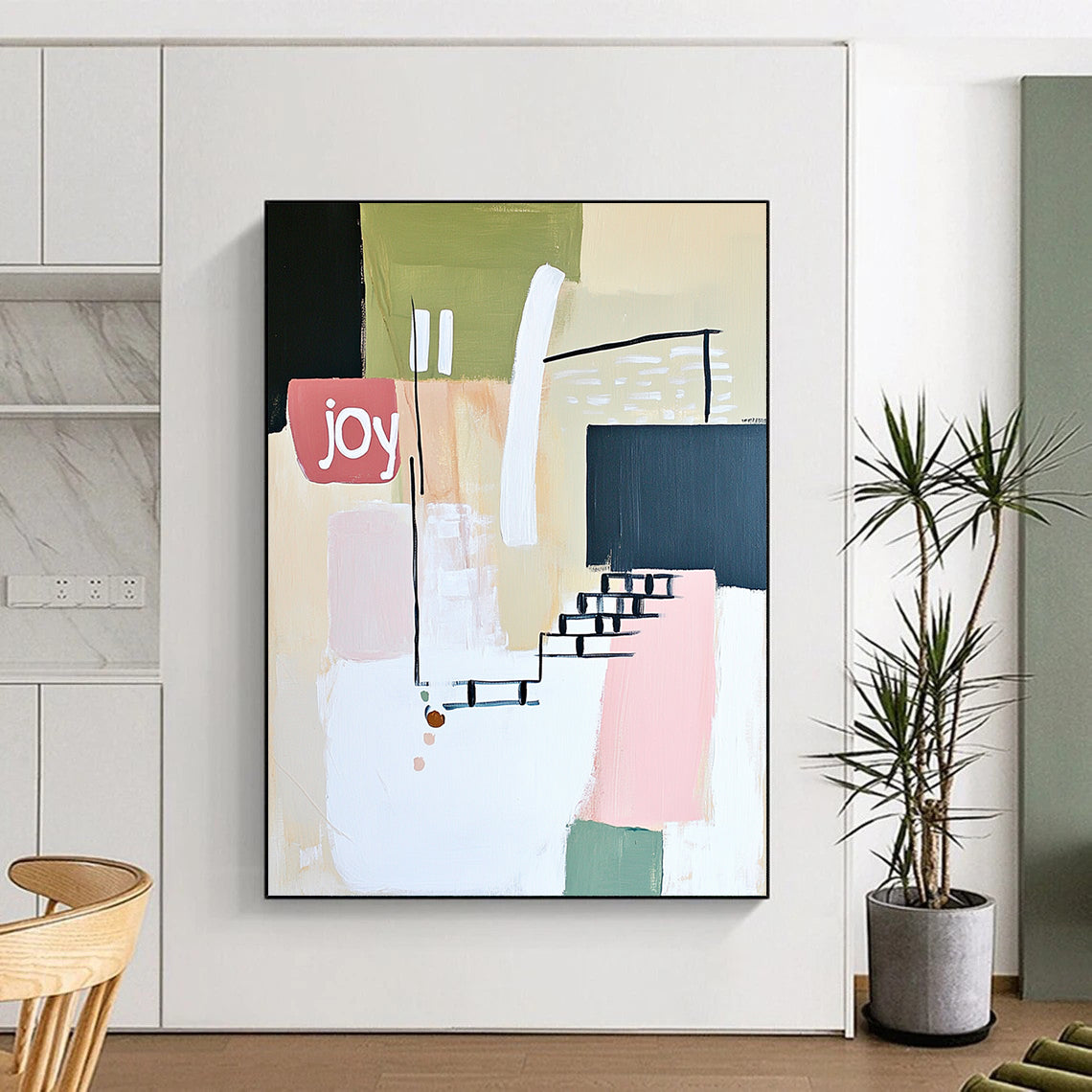 Contemporary abstract artwork features soft lines shapes and the word joy in white pale pink and green against a neutral background with a hint of staircase. DLZ1643
