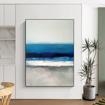 Large contemporary abstract painting featuring soft blues and grays capturing serene sea waves with a hint of deep blue for added depth. DLZ1359