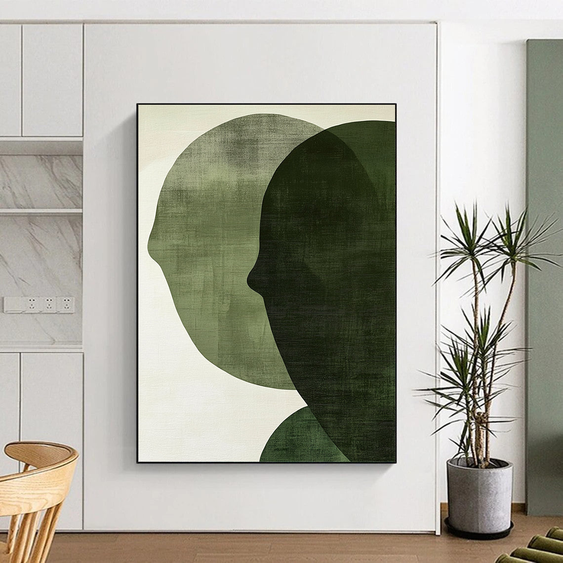 Contemporary abstract art features large forest green shapes on an off-white textured background, creating faces that symbolize connection and balance. DLZ1364